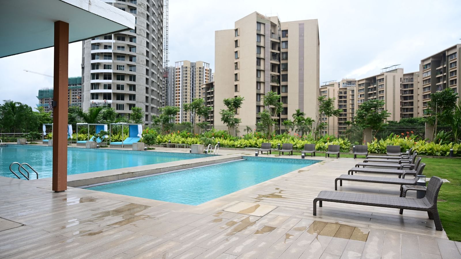 image featuring the swimming pool at club charholi, pune with sun loungers lined on the poolside